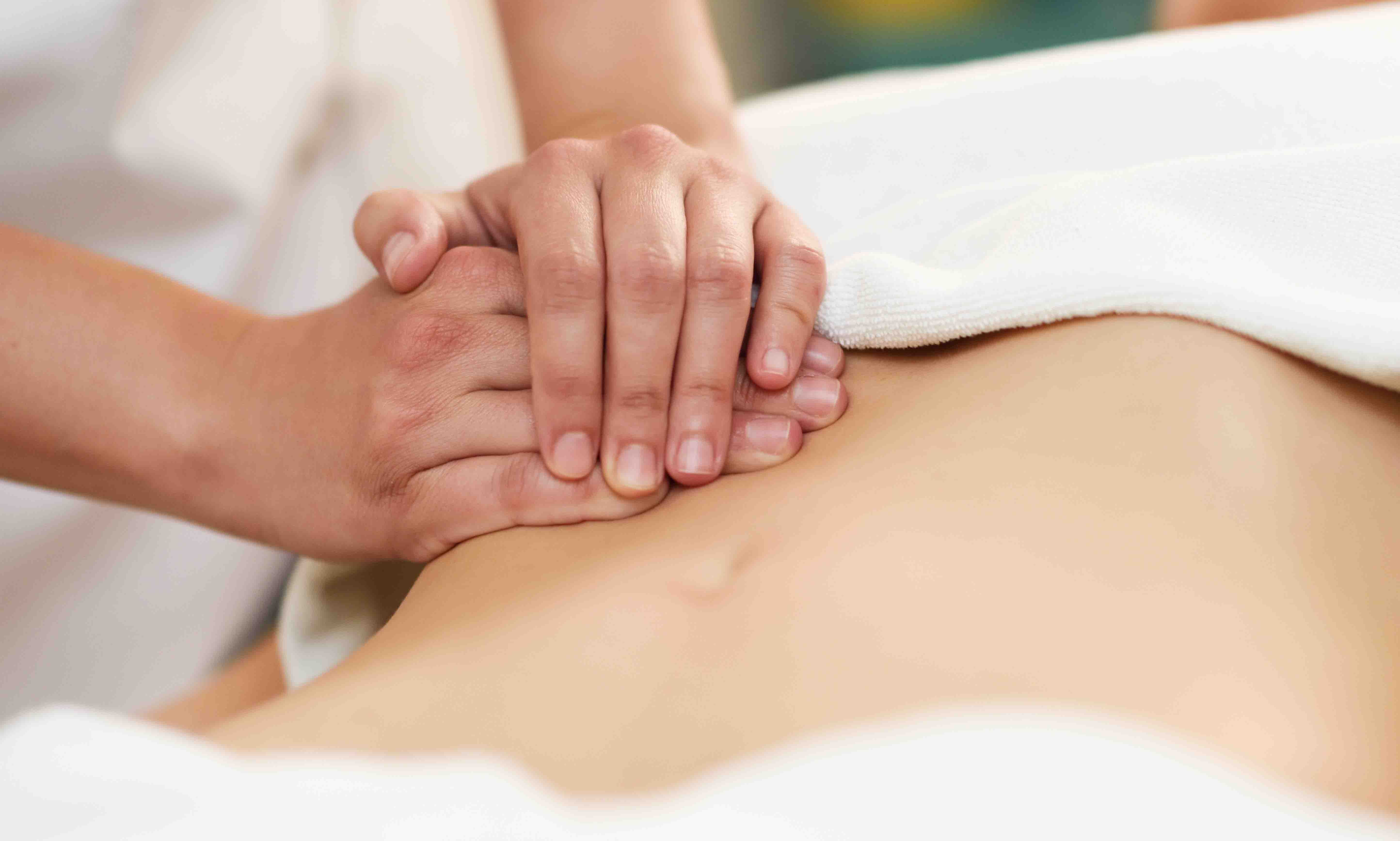 摄图网_300142486_治疗师腹部施加压力水疗沙龙接受按摩的女人双手按摩女腹部（企业商用）